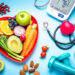 Healthy lifestyle concepts: red heart shape plate with fresh organic fruits and vegetables shot on blue background. A digital blood pressure monitor, doctor stethoscope, dumbbells and tape measure are beside the plate  This type of foods are rich in antioxidants and flavonoids that prevents heart diseases, lower cholesterol and help to keep a well balanced diet. High resolution 42Mp studio digital capture taken with SONY A7rII and Zeiss Batis 40mm F2.0 CF lens