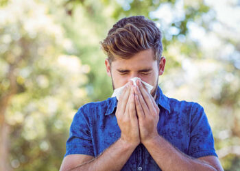 Handsome hipster blowing his nose on a sunny day