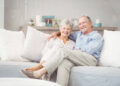 Portrait of romantic senior couple sitting on sofa in living room at home