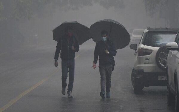 New Delhi, Jan 05 (ANI): People walk holding umbrellas amid light rain on a foggy winter morning, in New Delhi on Wednesday. (ANI Photo)
